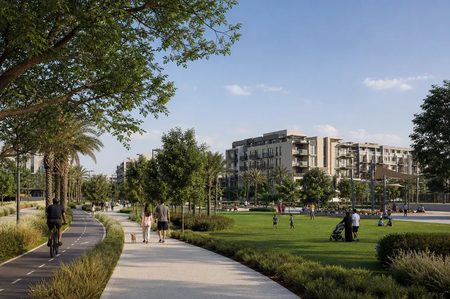 Families walking and cycling through the landscaped park at Dubai Hills Estate.