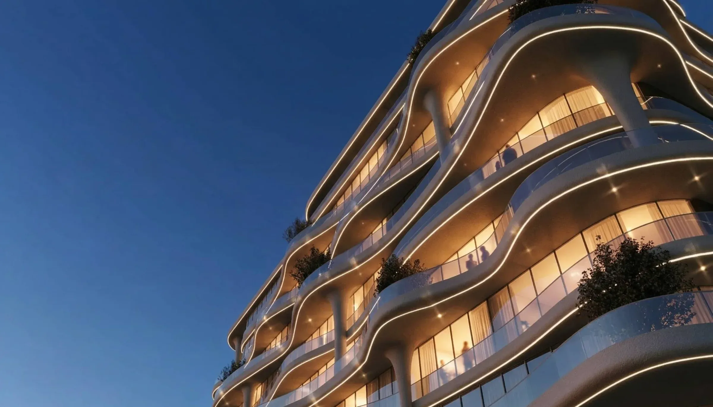 Curved illuminated façade of Coralis Grand Residences at dusk